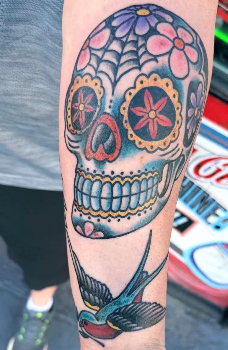 Color sugar skull and swallow tattoo in a bold traditional style