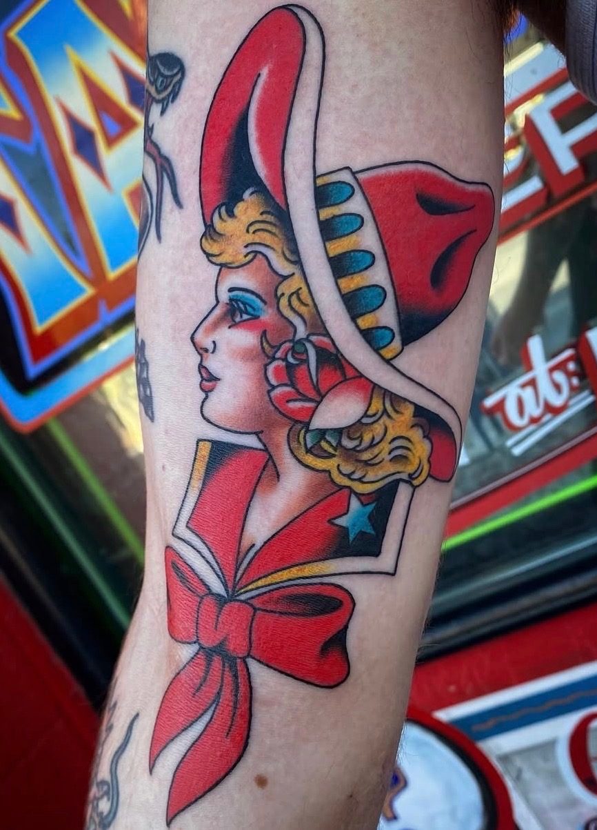 Bold traditional color cowgirl tattoo with a red hat, rose and bow completed at Last Chance Tattoo in Las Vegas